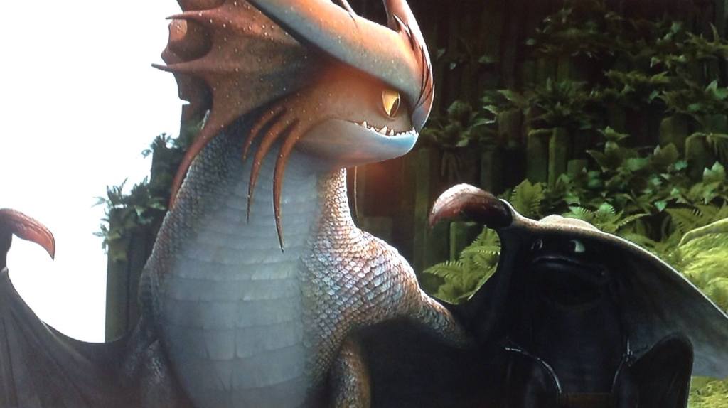 In a scene from How to Train Your Dragon 2, Toothless plays with a large, colorful dragon.